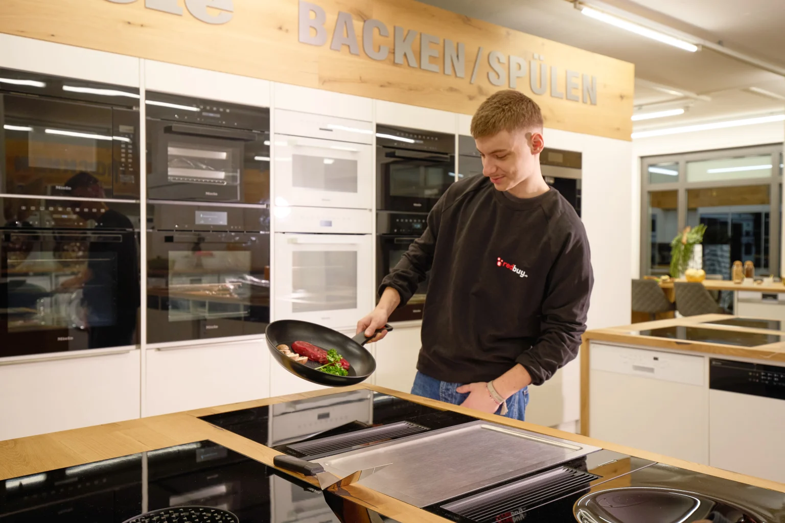 Mitarbeiter der Redbuy GmbH berät am Kochfeld im Showroom Winterthur